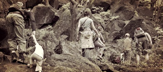 family climbing over boulders on a hike
