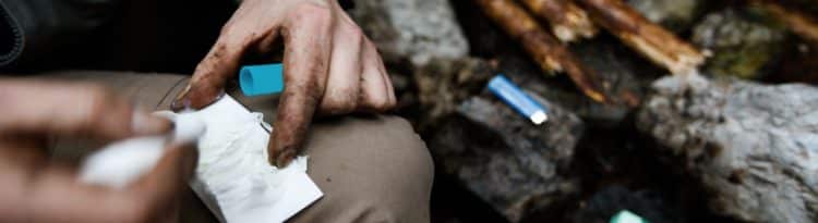 Man lighting a fire with help of a lip balm