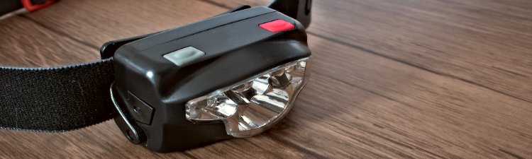 Black led headlamp turned off on a wooden table showing the elastic strap