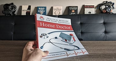 Holding the Home Doctor Book With Prepping Background (c)